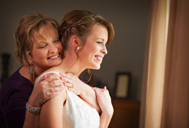 a woman in a purple shirt is hugging a woman in a white dress
