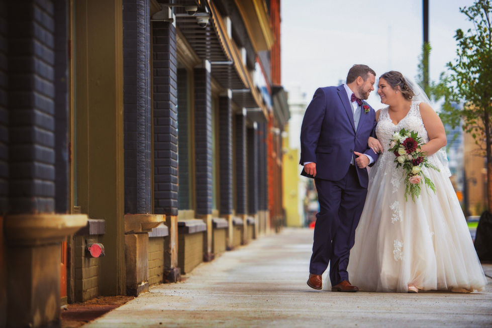 a bride and groom are walking down a sidewalk