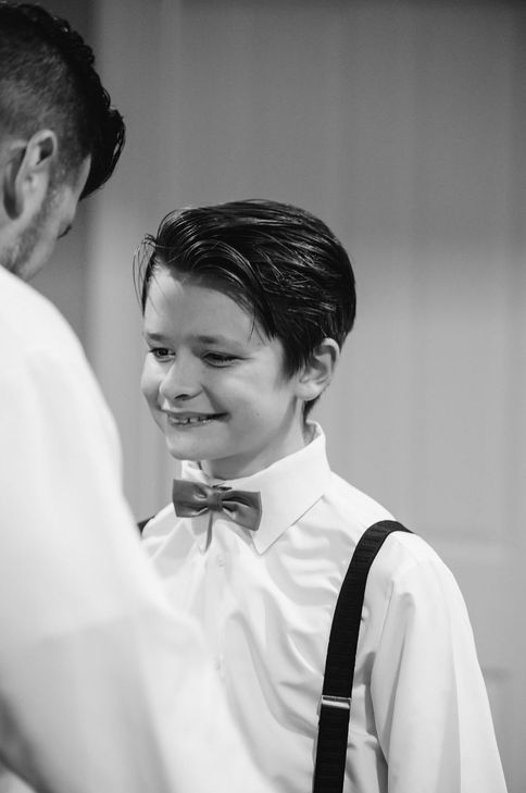 a young boy wearing a bow tie and suspenders smiles for the camera
