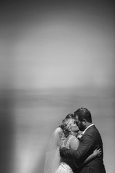 a black and white photo of a bride and groom kissing on the beach
