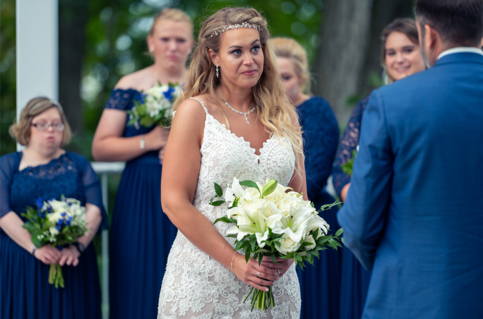 a woman in a wedding dress holds a bouquet of white flowers