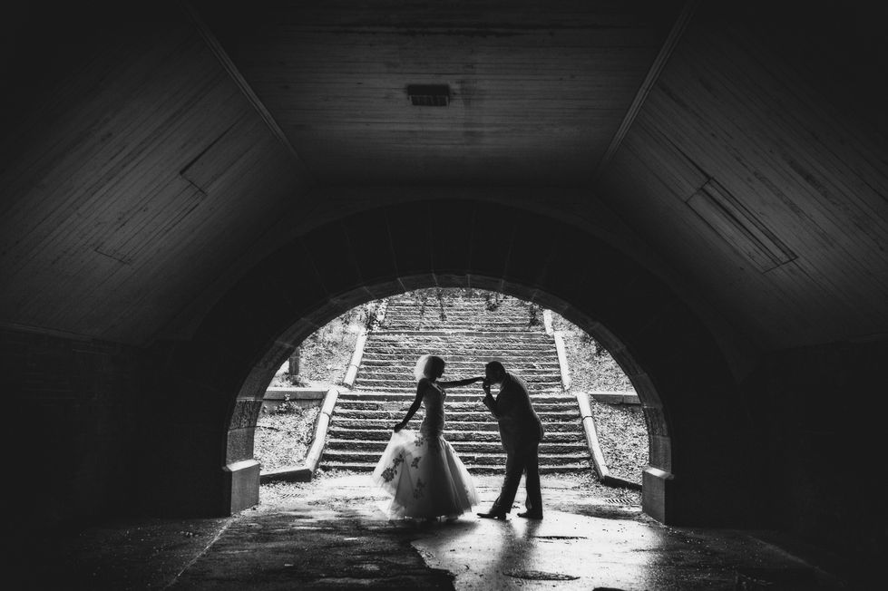 a black and white photo of a bride and groom in a tunnel