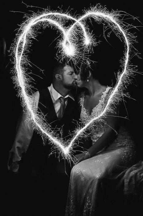 a bride and groom kissing with sparklers in the shape of a heart