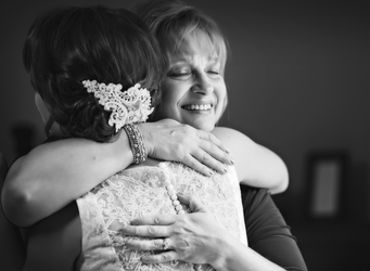 a woman in a wedding dress is hugging another woman