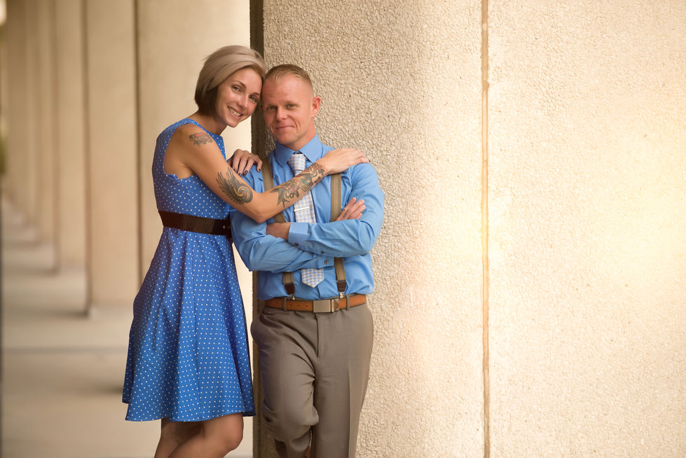 a woman in a blue dress is hugging a man in suspenders