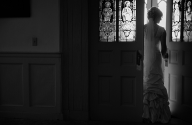 a bride stands in front of a stained glass window