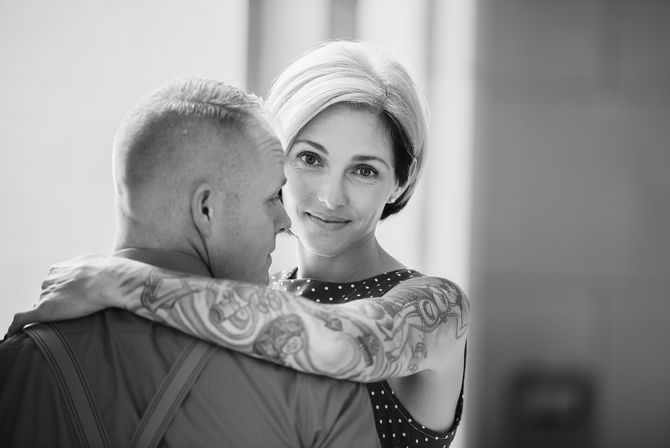 a woman with a tattoo on her arm is hugging a man