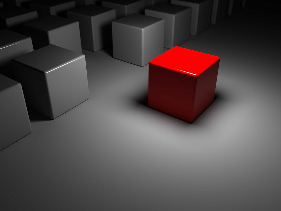 A dark photo, with light over the center showing a red block surrounded by many grey and black blocks