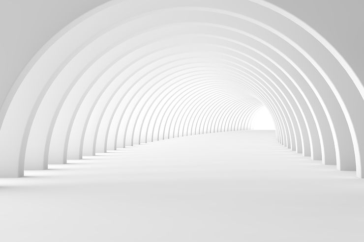 A long white tunnel, with countless white arches extending along the tunnel as it curves off to the right in the distance