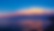 Colorful sunset over a calm lake and sandy beach, with pink-orange clouds glowing against a deep blue sky.