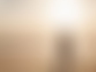 Silhouettes of a man and child walking on a sunlit beach with gentle waves. The sky is golden, suggesting a peaceful, serene evening.