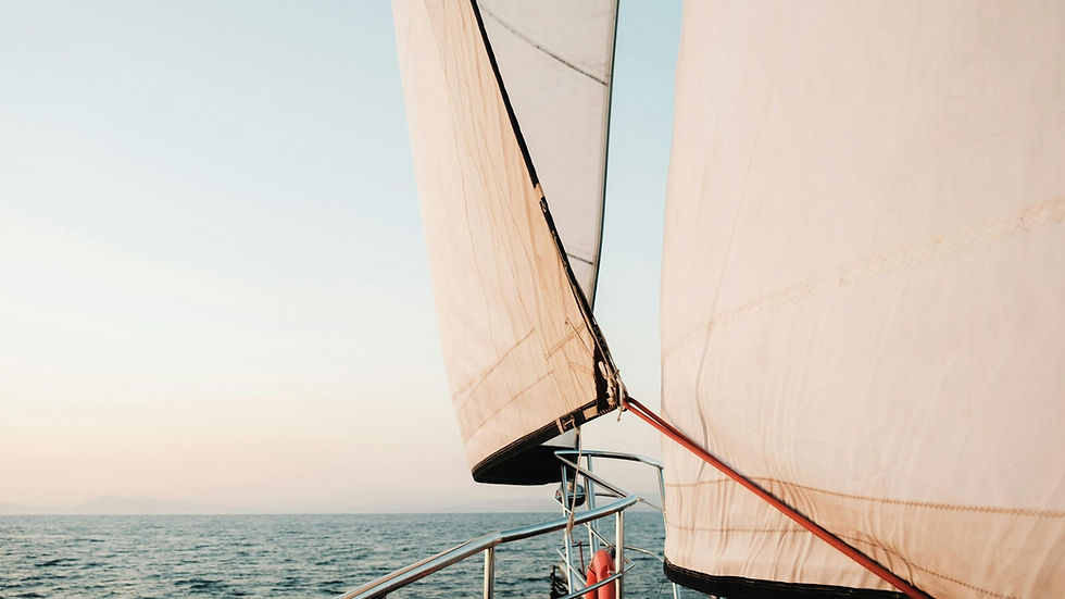 Close-up of white sailboat sails on calm lake at sunrise, with metal railing and soft pastel sky, tranquil mood