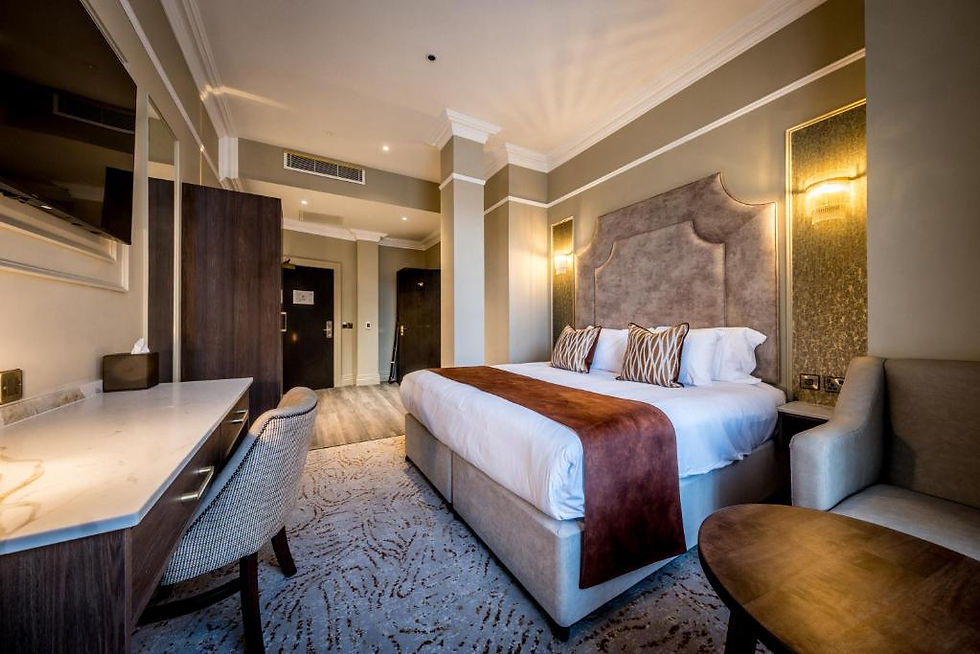 Chambre d’hôtel moderne et vide, lit king-size, bureau, fauteuil et lumière chaude, ambiance calme et élégante.