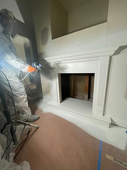 Painting contractor spraying indoor fireplace