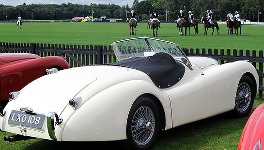 White-jaguar-xk-parked-in-front-of-polo-field-with-players-on-horses.jpg