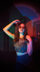 Editorial portrait photography featuring a subject in dramatic red and blue lighting with urban framing and cinematic contrast.