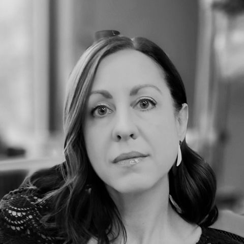 Black and white portrait of a woman with shoulder-length dark hair, a lace black top and the hint of a silver earring.