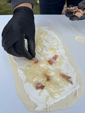 Some cheese and bacon is put on a rolled out dough with creme fraiche