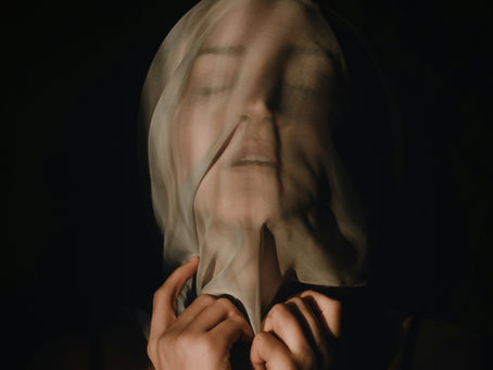 Une femme soulève le voile qu'elle a sur le visage.