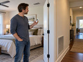 Homeowner comparing bedroom and hallway temperatures near HVAC supply and return vents