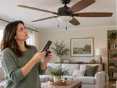 Homeowner checking fresh batteries in a ceiling fan remote while looking at a stationary fan.