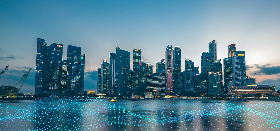 City skyline at dusk with illuminated skyscrapers. Blue lights ripple across the water. Sky transitions from blue to orange. Calm mood.