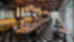 Chic restaurant with yellow booths, checkered floor, and warm lighting. Tables set with glassware. Large windows, modern decor.