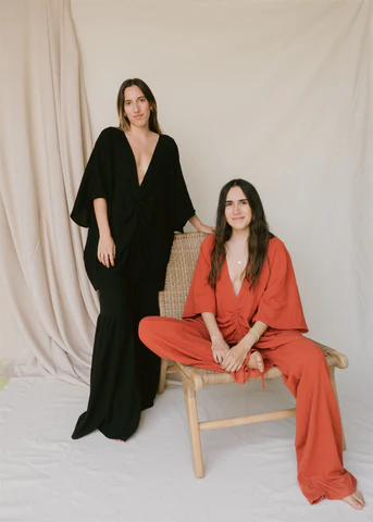 2 mexican women wearing black and rust on off white background looking elegant