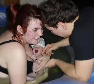 Elated new mother and birth partner with newborn baby after calm hypnobirth in birthpoolin