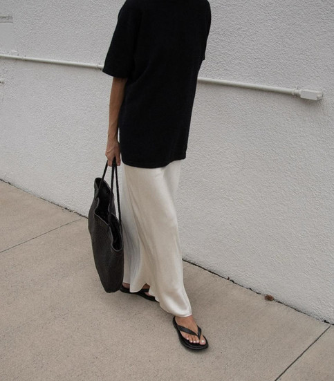 Girls wearing a silk cream skirt with black t shirt and flip flops