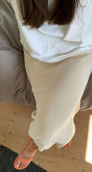 girls wearing a cream skirt orange flip flops and white tee
