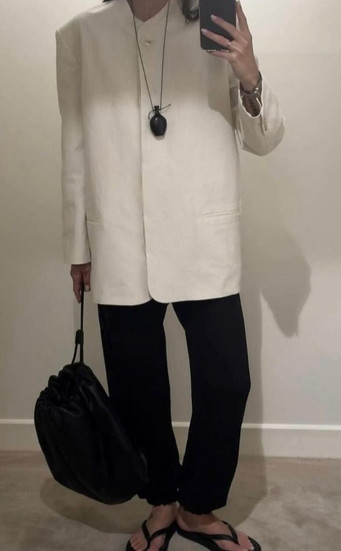 A girls in cream blazer black trousers and flip flops 