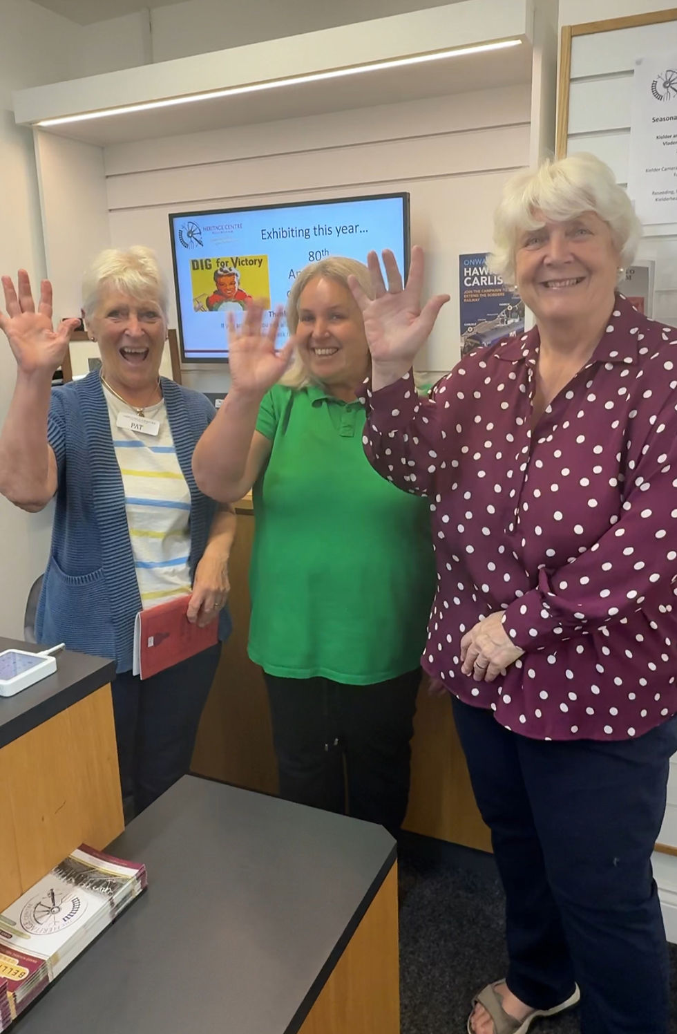 Three women smiling and waving.