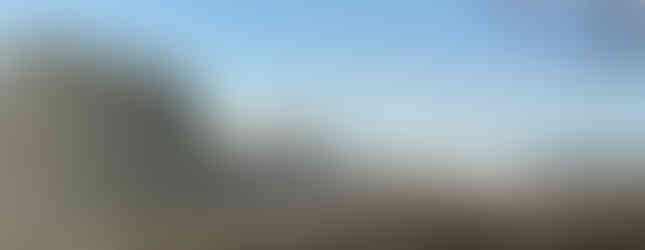 Rolling hills with stone wall and trees under a bright blue sky curiuscompass