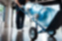 cropped view of delivery man in uniform holding hand truck with purified water in bottles