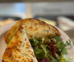 A croque monsieur served on a plate with salad.