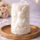 Thumbnail: Elegant white pillar candle with embossed bunny and floral design on gold tray.