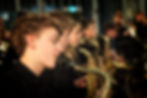 A young saxophone player playing in a line of other sax players