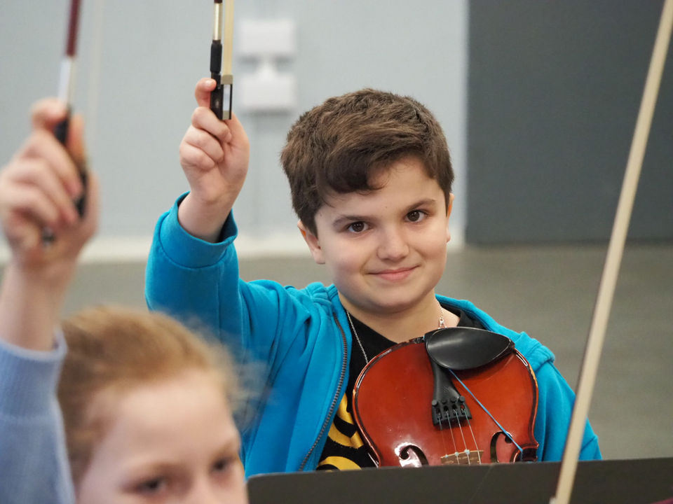 a young violinist with his bow in the air
