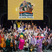 The orchestra and production team gather around the big screen for a group photo