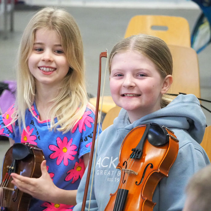 Young violinists smiling with their instruments