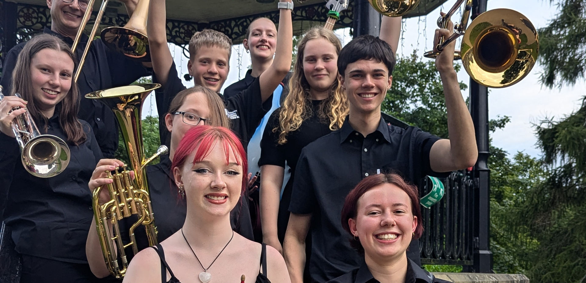 A group of musicians stand in a band stand smiling