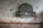 Broken, weather-worn bird cage on wall.