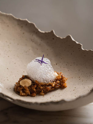 Un plato cerámico de arroz cremoso, liebre y aire de lavanda