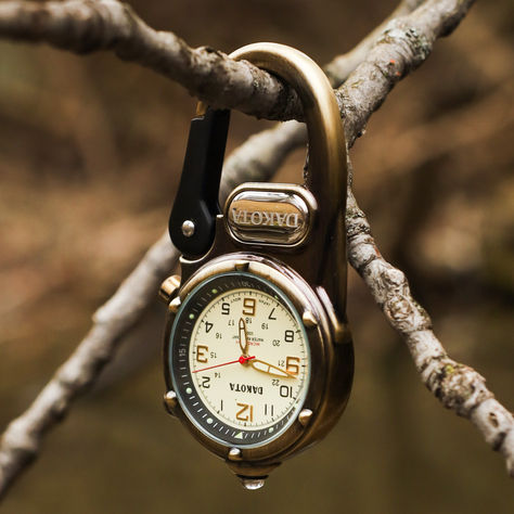 Dakota Miniclip Microlight watch in Antique Brass hanging on a brand in the woods.