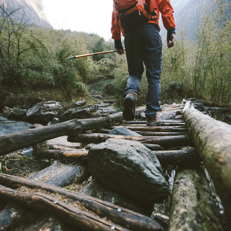 Person walking on a handmade wooden bridge over a river