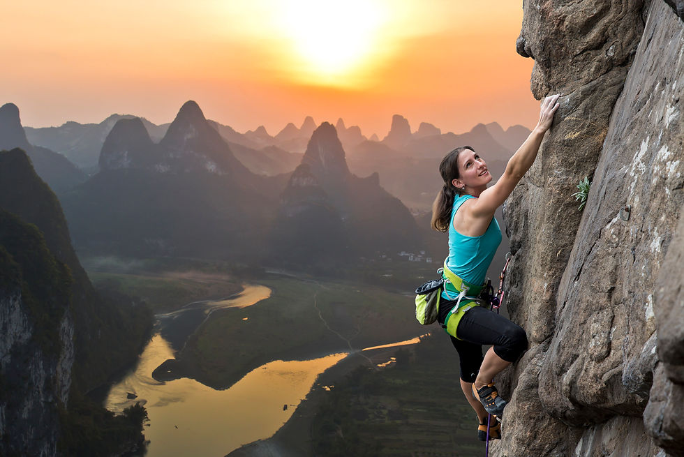 Young woman climbing a mountain with a horizon of mountains behind her