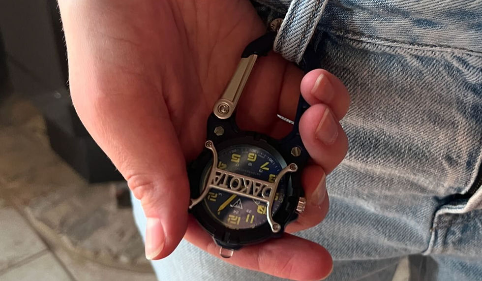 Dakota Cage watch in blue clipped to blue jeans, held by hand