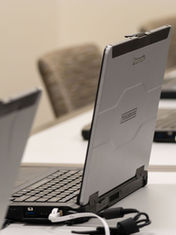 A row of open laptops on a table with one of the laptops in focus