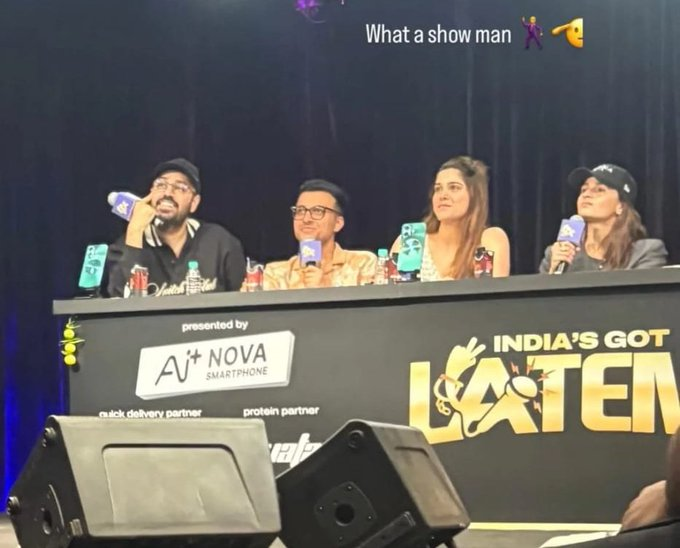 Four judges sit at a panel for "India's Got Talent," microphones in hand, smiling. Background is dark, text reads "What a show man."